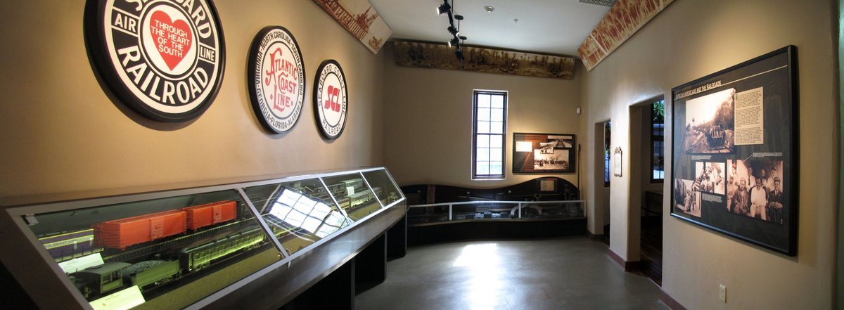 Wide panoramic gallery view showing railroad logos, custom display cases, and interpretive panels